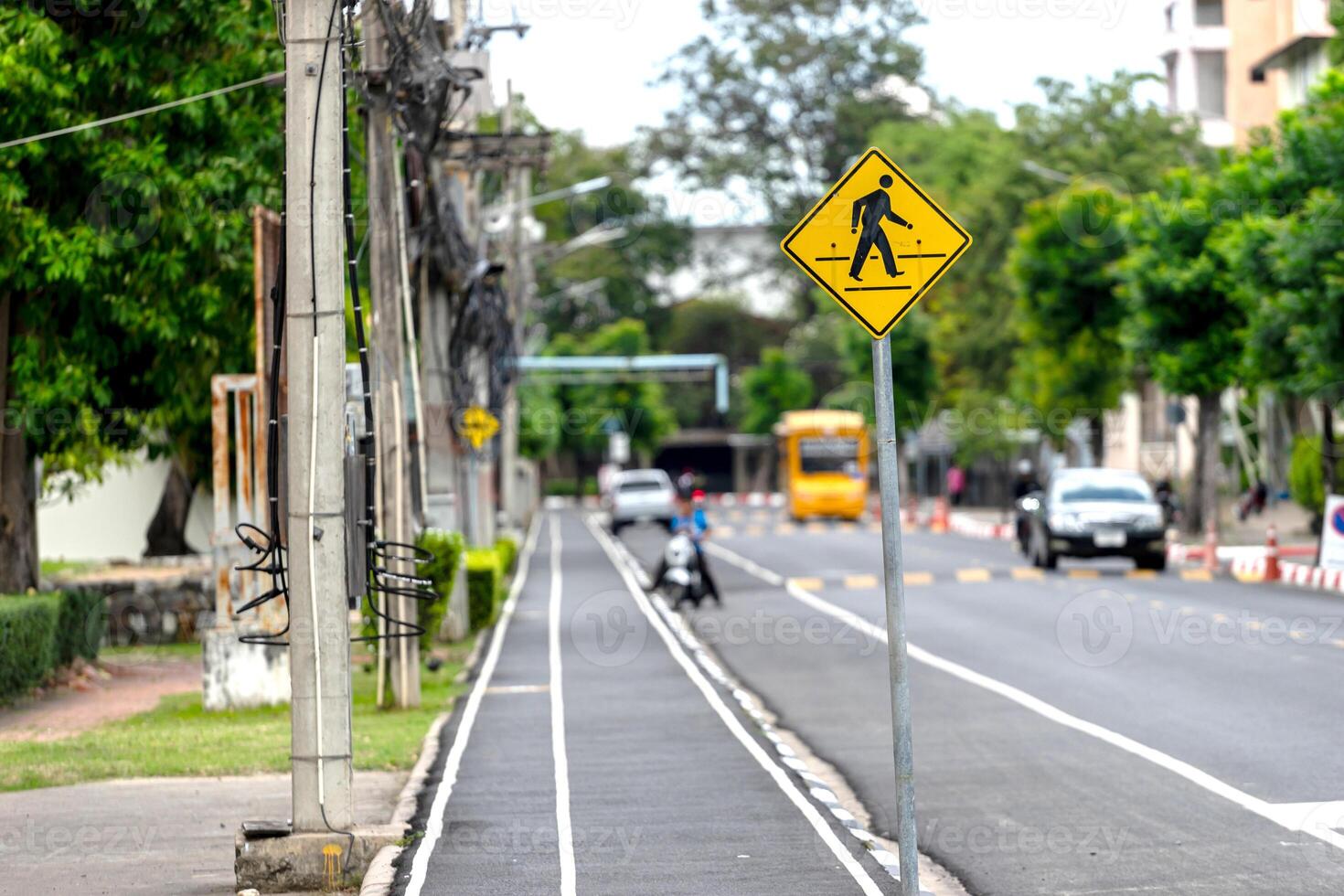 A yellow pedestrian crossing sign on a street photo