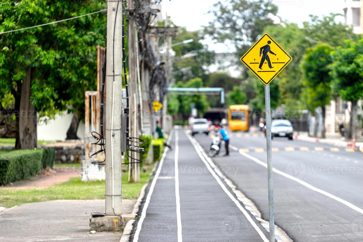 A yellow pedestrian crossing sign on a street photo