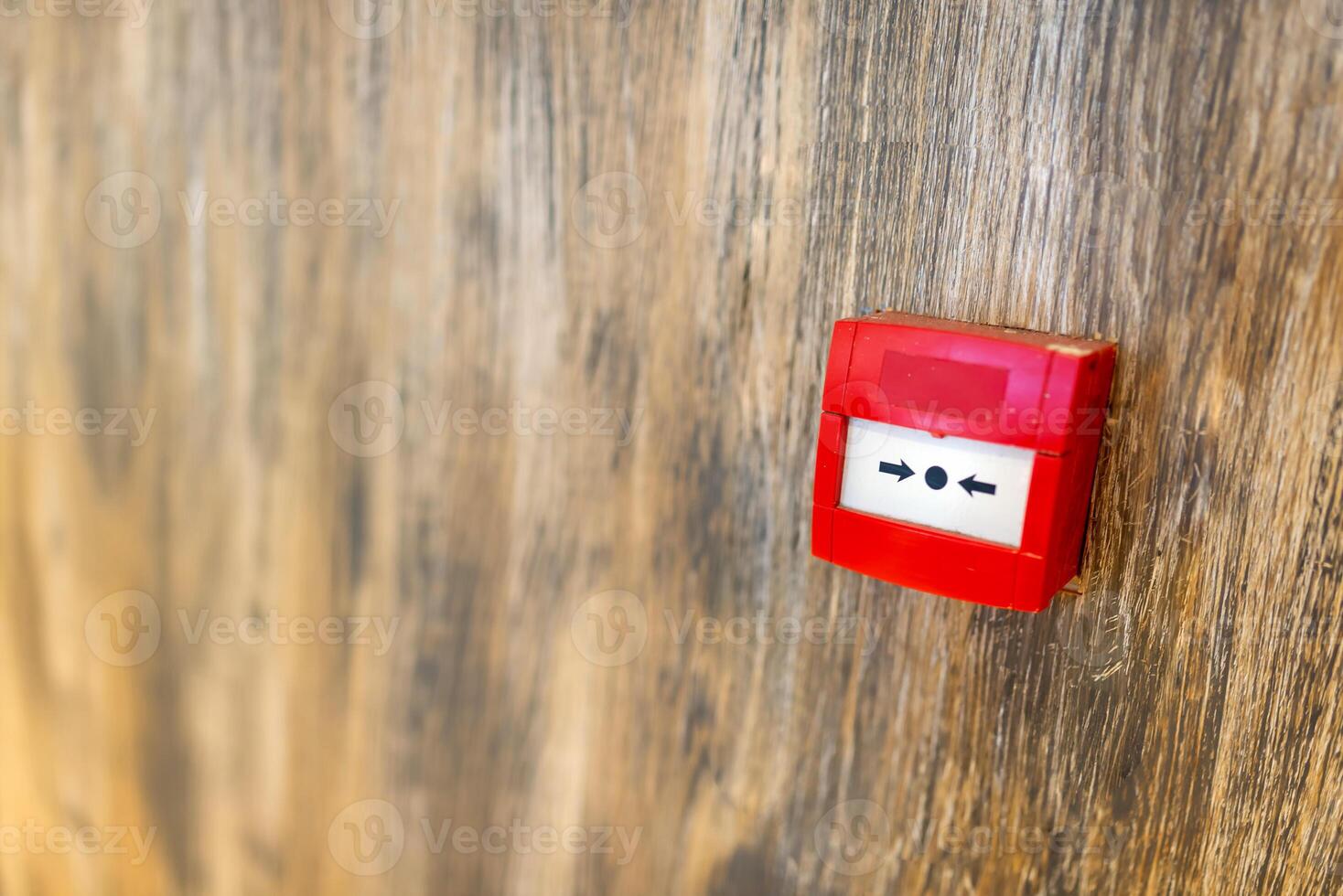 A red button on a wooden wall photo