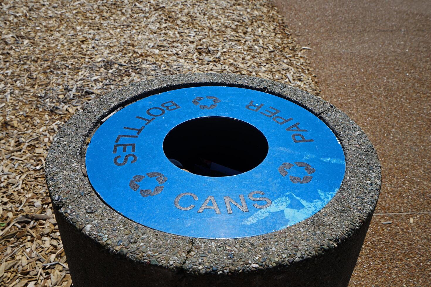 Blue recycle bin made of metal and concrete cement in public garden park photo