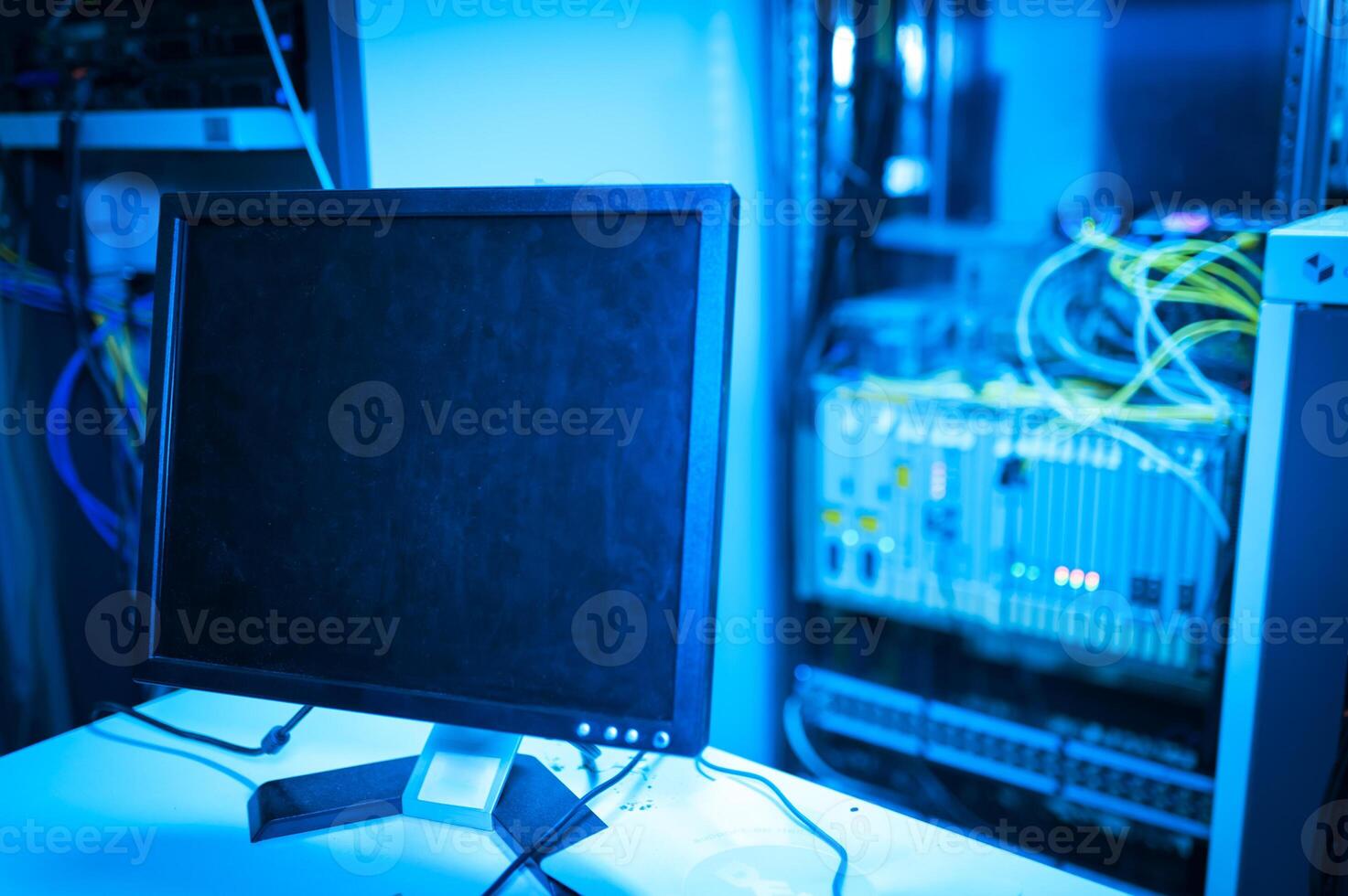 A computer monitor sitting on a desk in a server room photo