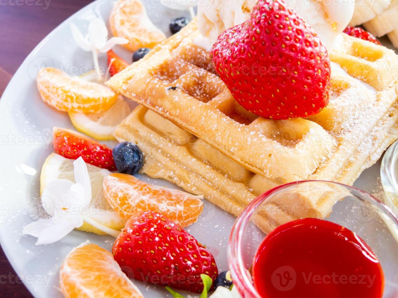 A plate of waffles with fruit and a bowl of fruit photo