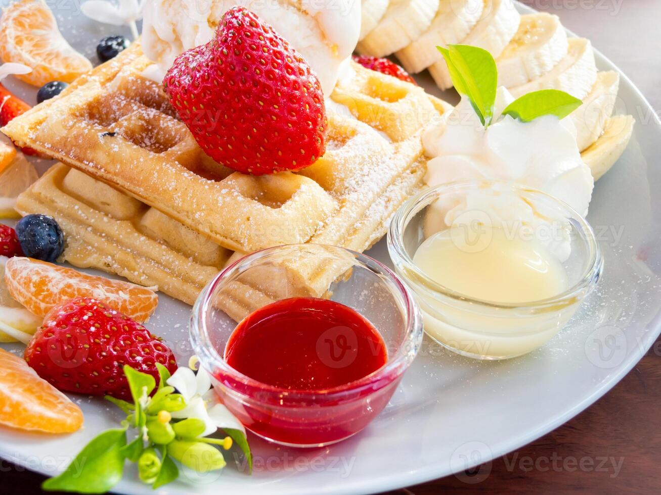 A plate of waffles, fruit, and a cup of juice photo