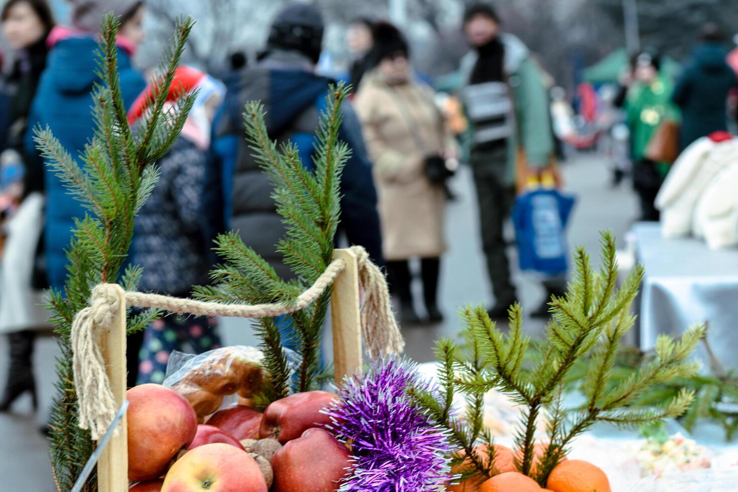 Basket of apples and fir branches at the Christmas market. people on blurred background photo