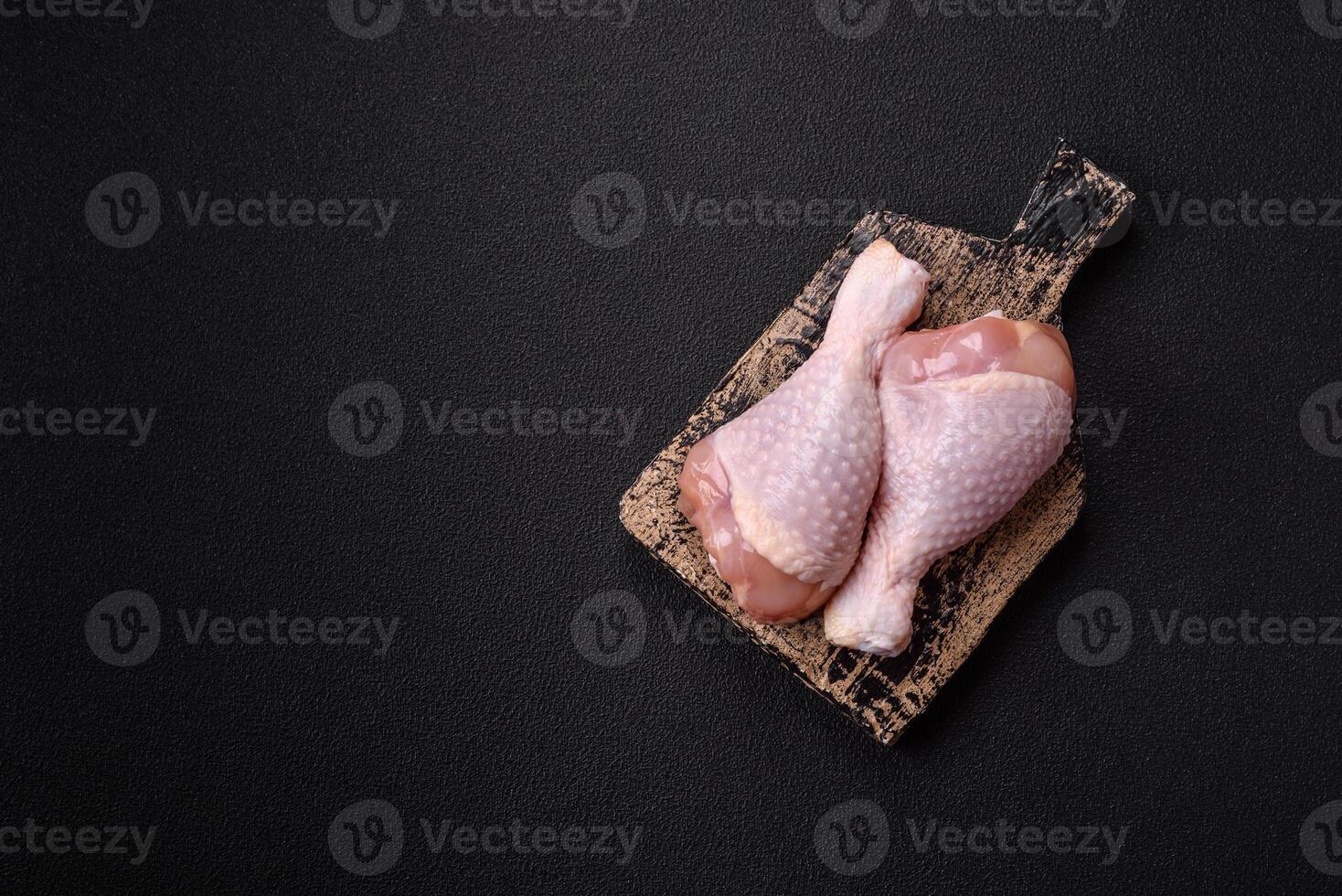 Raw chicken legs with salt, spices and herbs photo