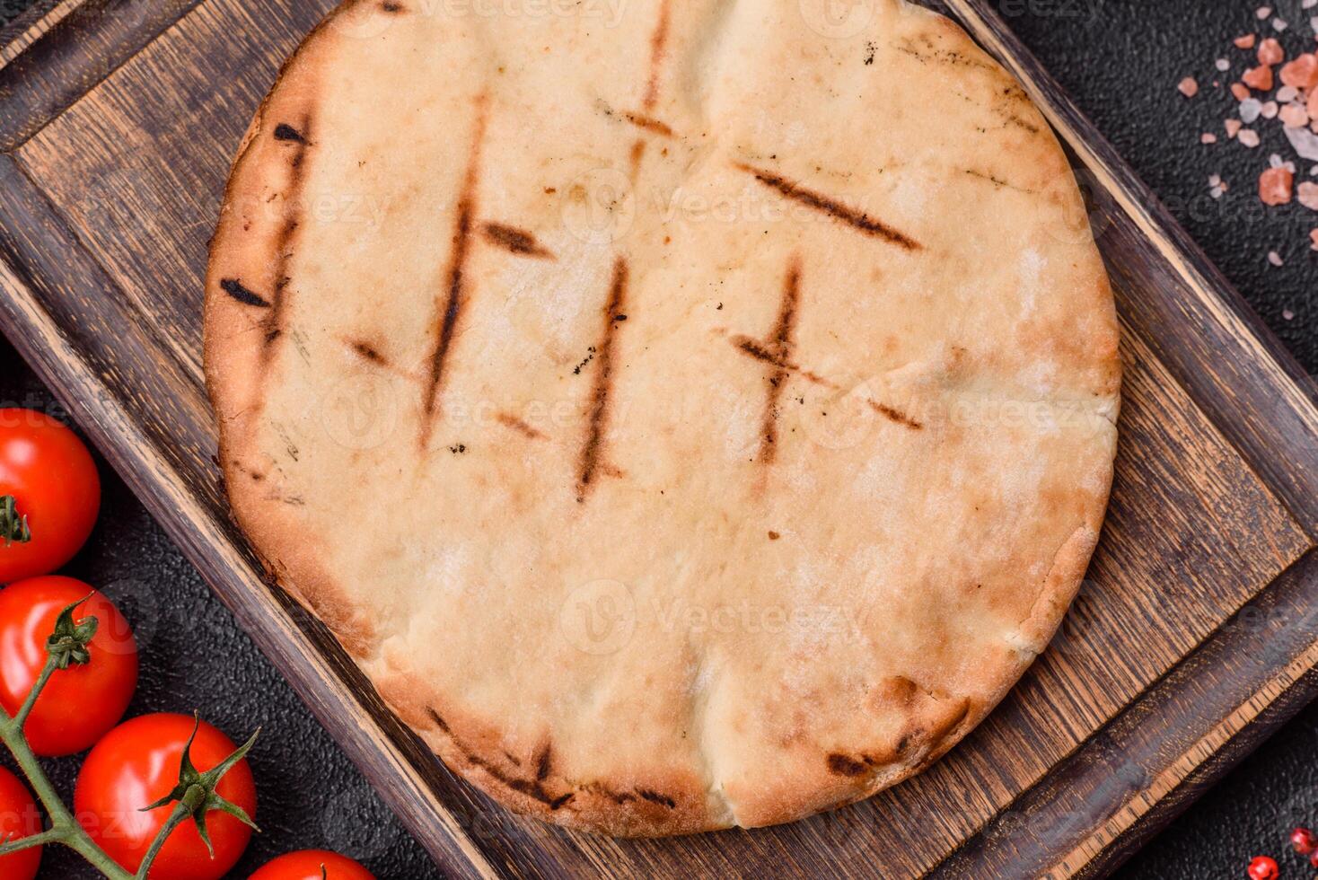 Round flatbread or pita with cheese, herbs, salt and spices photo