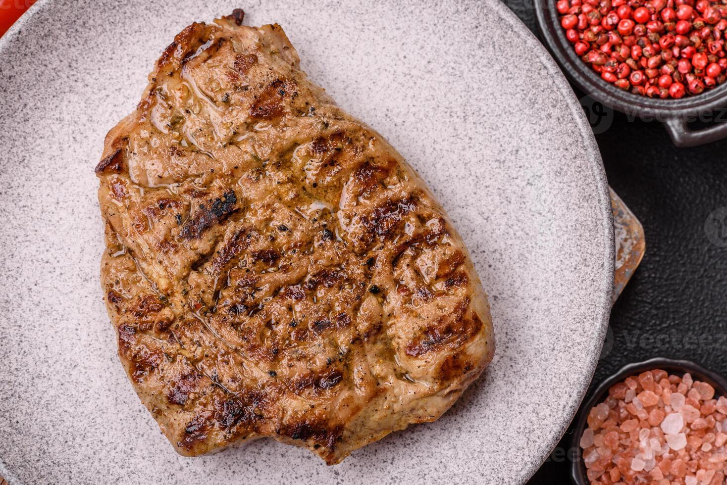 Grilled beef or pork steak with salt, spices and herbs photo
