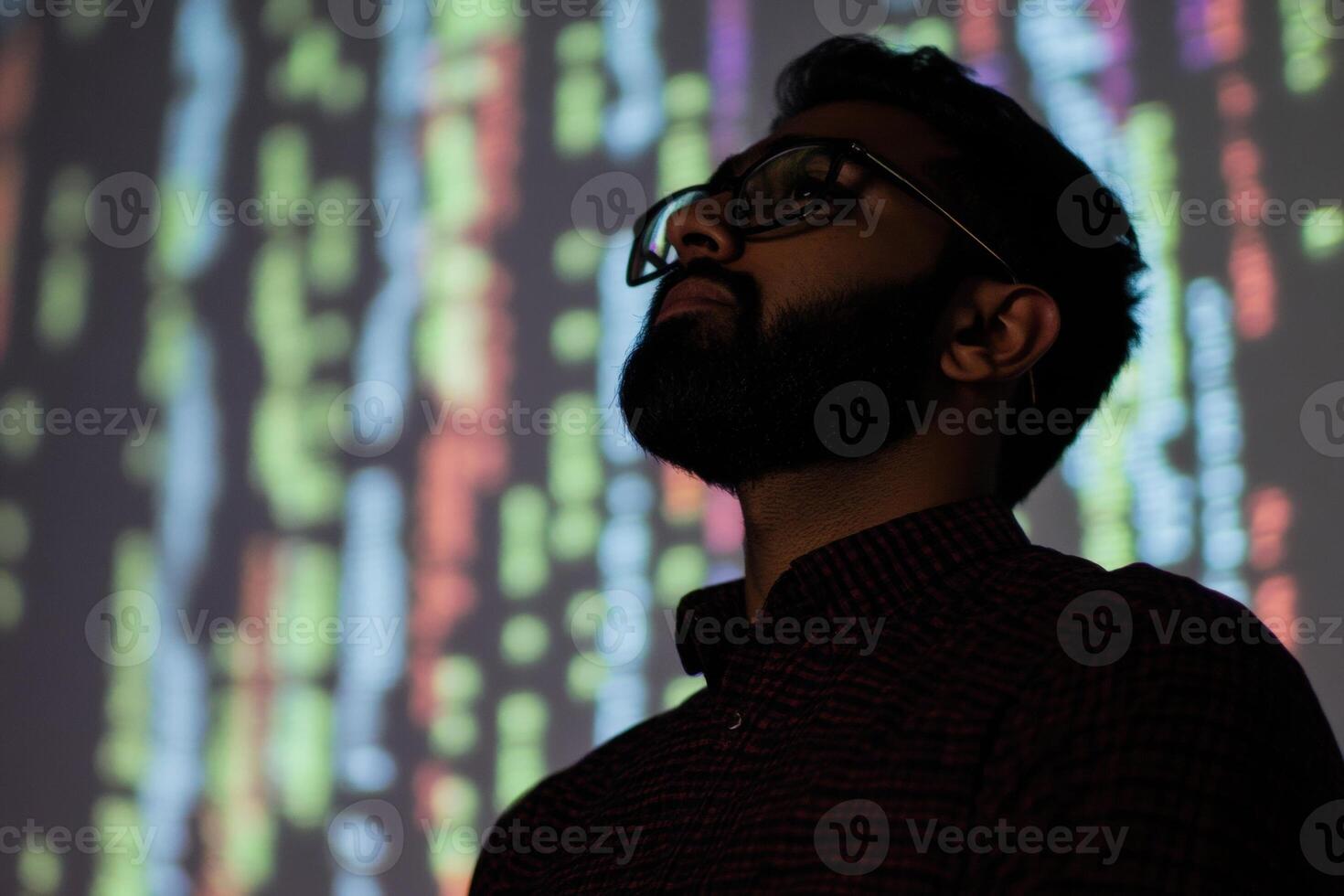 Indian programmer analyzing code projected on wall in office photo