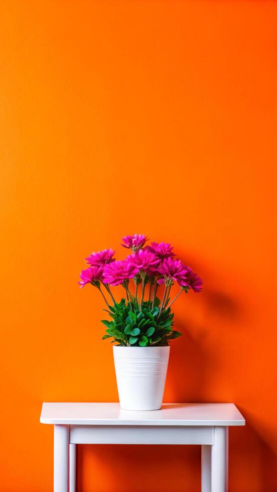 A white table with a flower pot on it against an orange wall photo