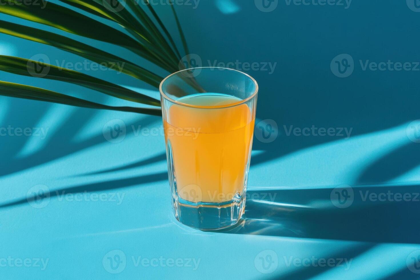 Refreshing tropical orange juice with palm leaf shadow on vibrant blue background photo