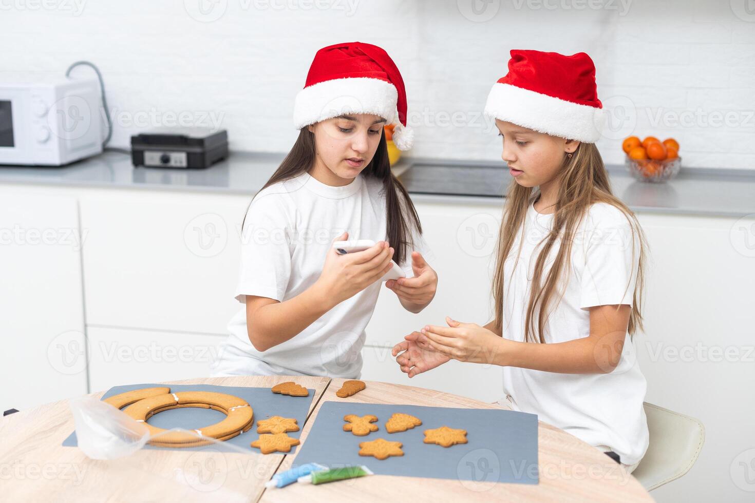 Two girls sisters are playing around in the kitchen after making Christmas cookies, they draw with flour on the table and on their faces. Christmas, New Year concept photo