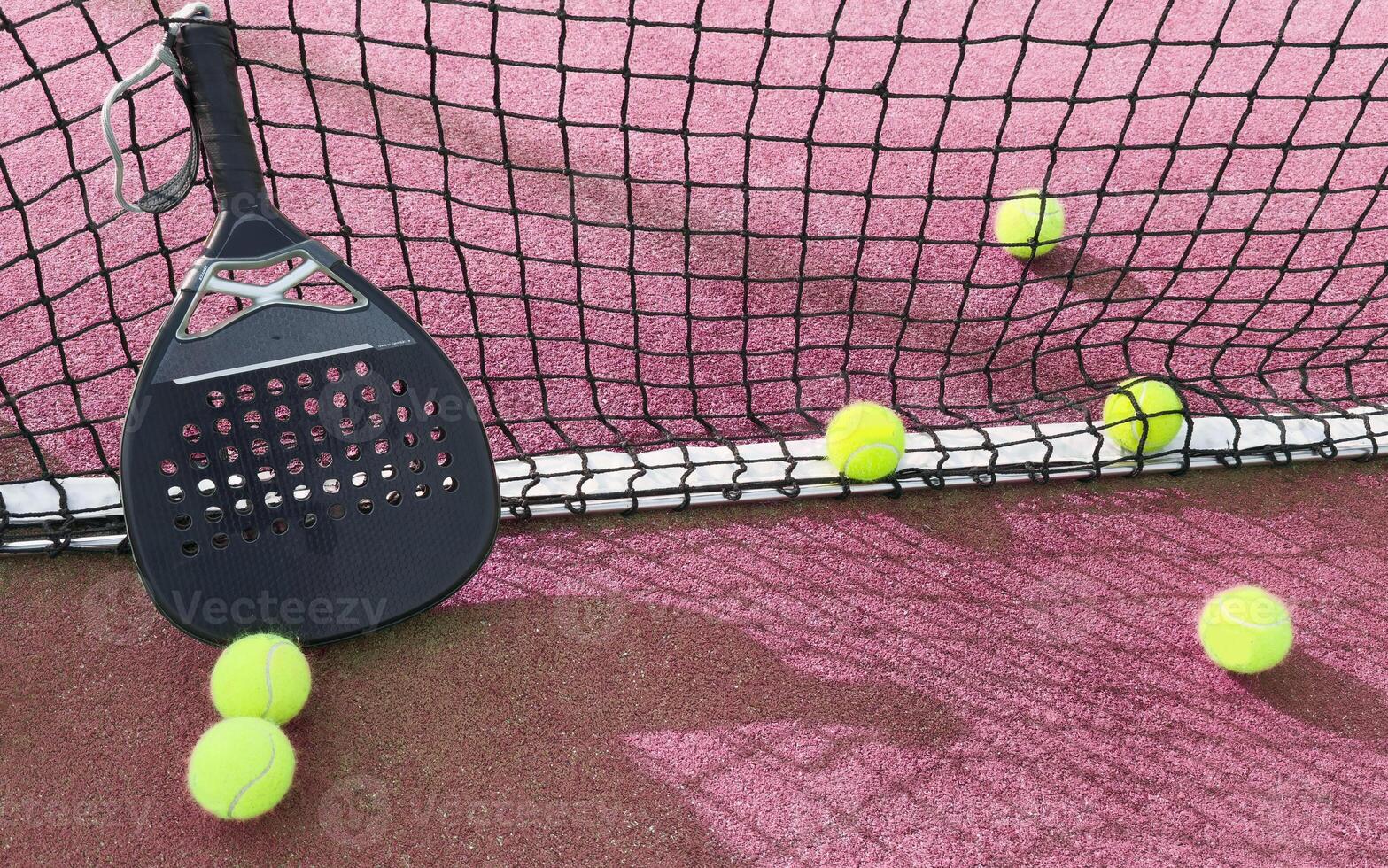 padel racket and yellow balls placed on court near net on sunny day photo
