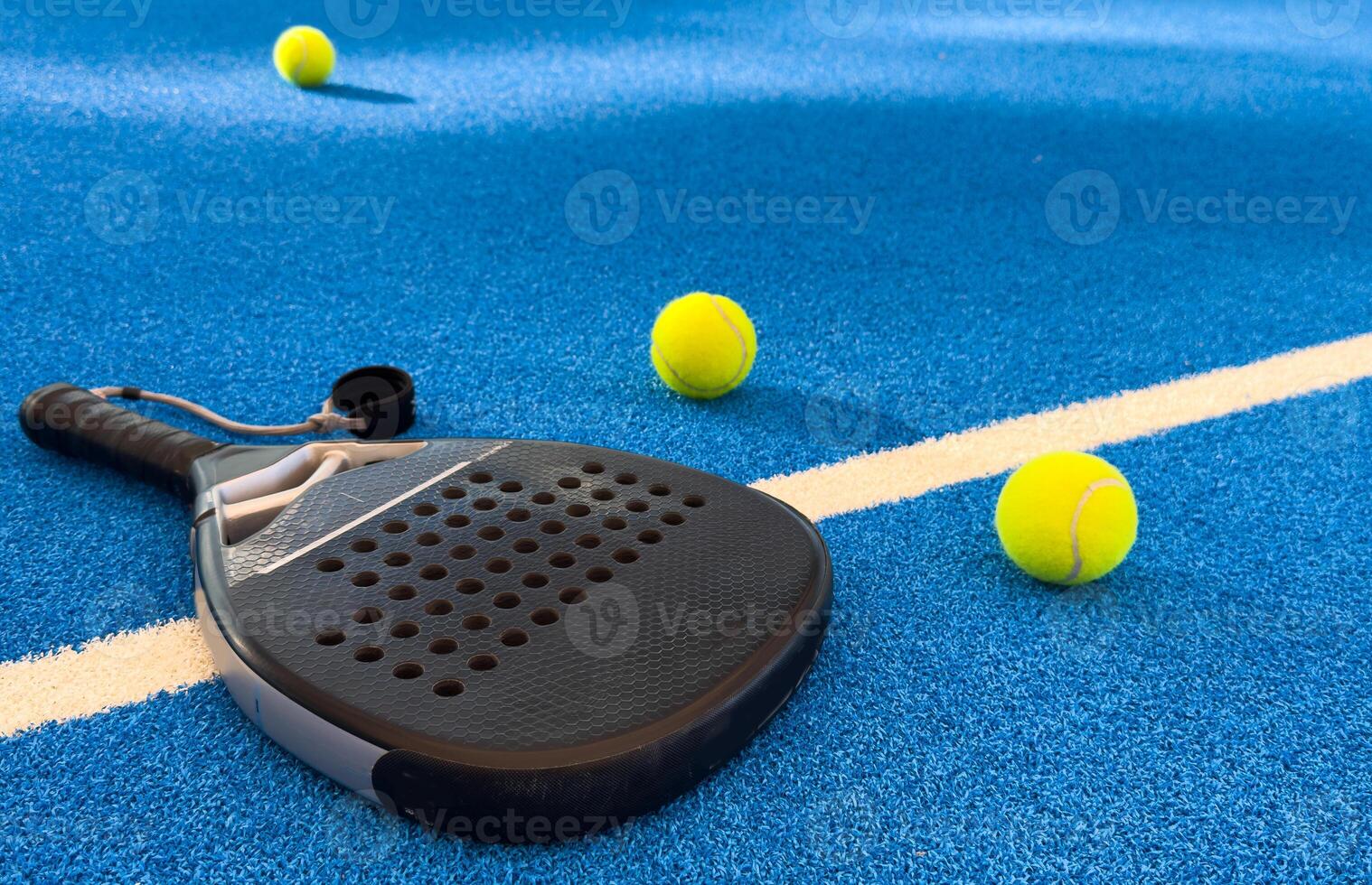 Black professional paddle tennis racket and ball with natural lighting on blue background. Horizontal sport theme poster, greeting cards, headers, website and app photo