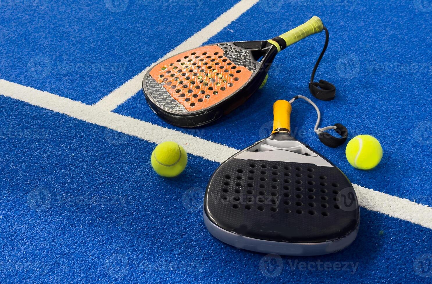 Black professional paddle tennis racket and ball with natural lighting on blue background. Horizontal sport theme poster, greeting cards, headers, website and app photo