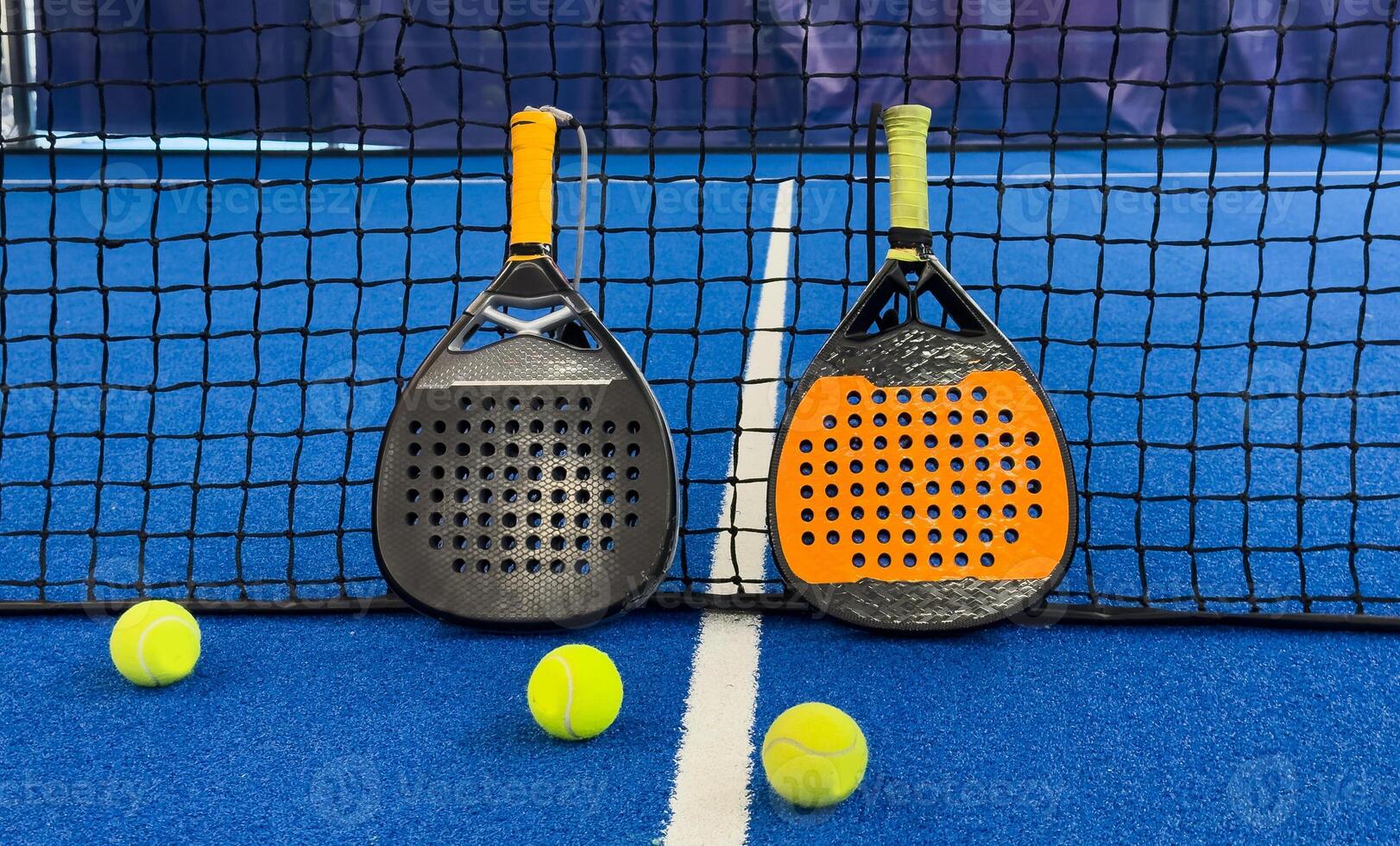 Black professional paddle tennis racket and ball with natural lighting on blue background. Horizontal sport theme poster, greeting cards, headers, website and app photo