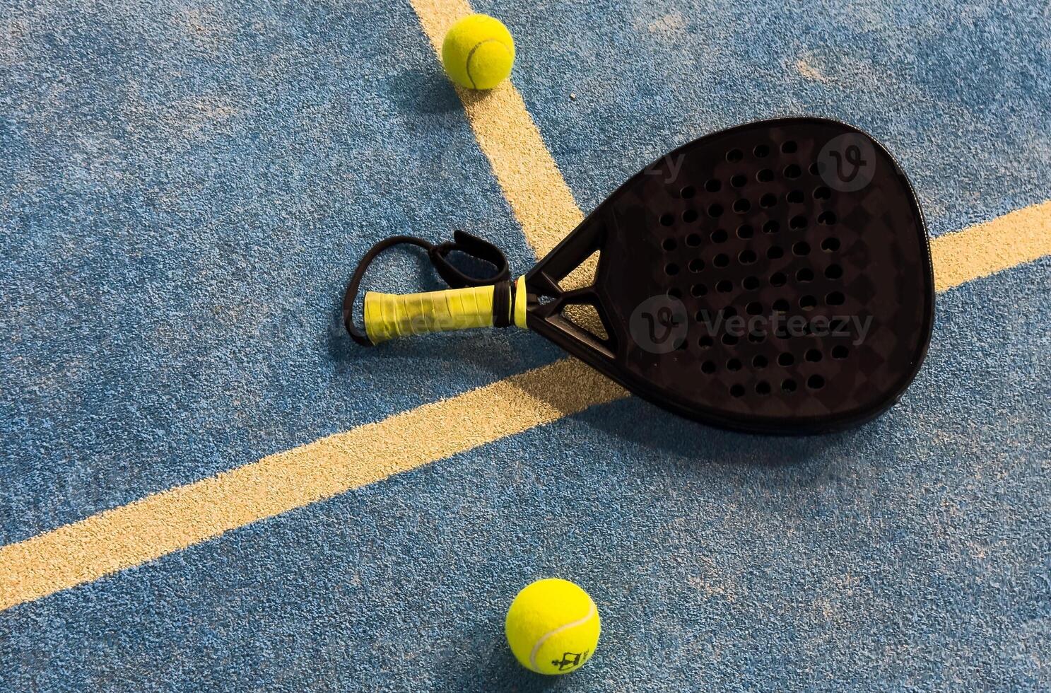 padel racket and yellow balls placed on court near net photo