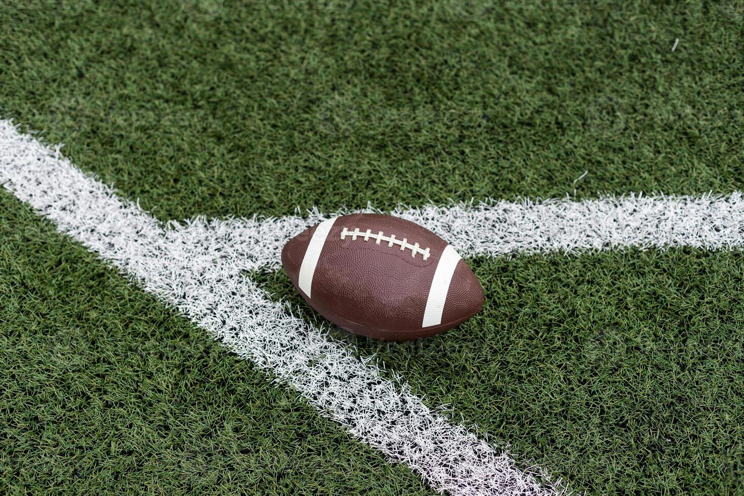 Close up view of an American Football sitting on a grass football field on the yard line. Generic Sports image photo