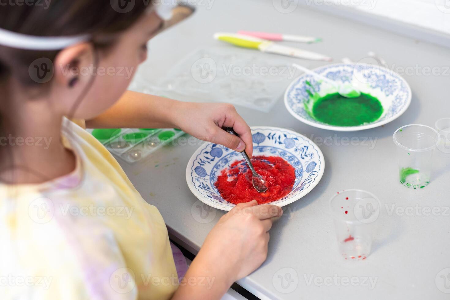 child learning research and doing a chemical experiment while making analyzing and mixing liquid in test glasses. Playful little girl in protective wear having fun playing with chemistry lab game photo