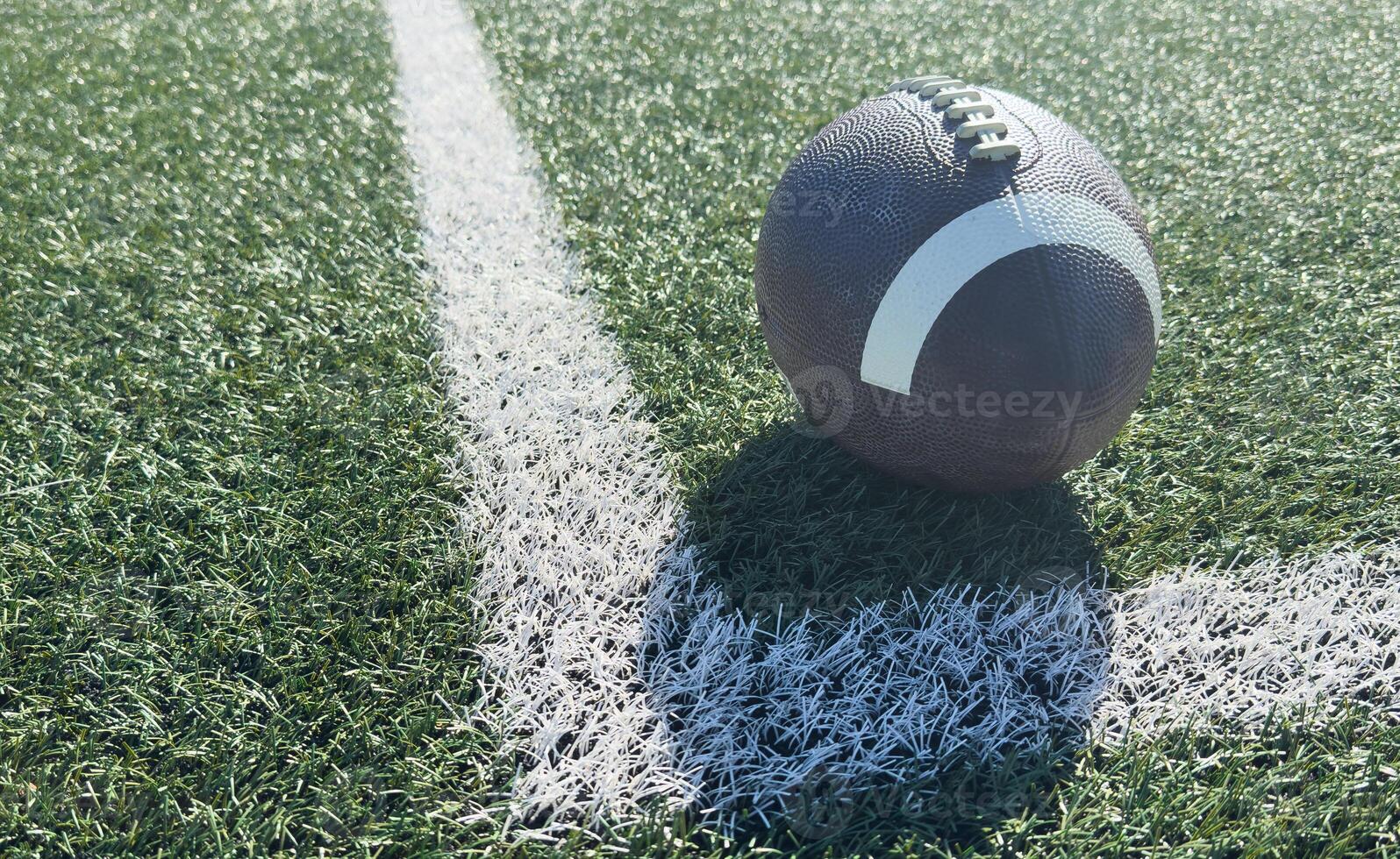 Close up of an american football on the field, players in the background photo