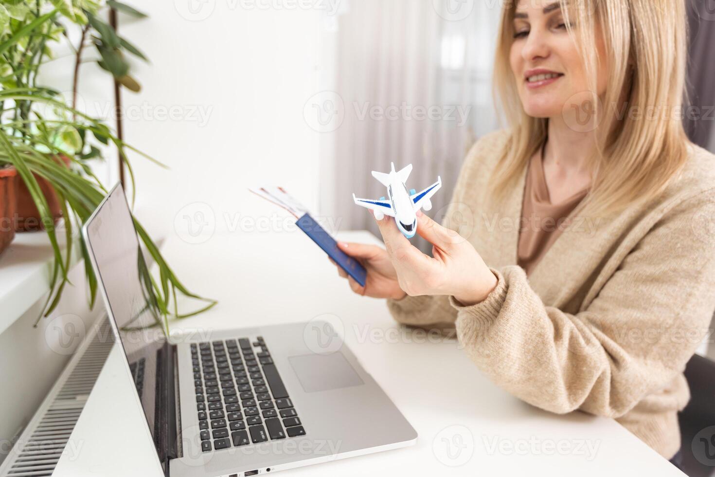 woman holding toy plane, tickets, laptop photo