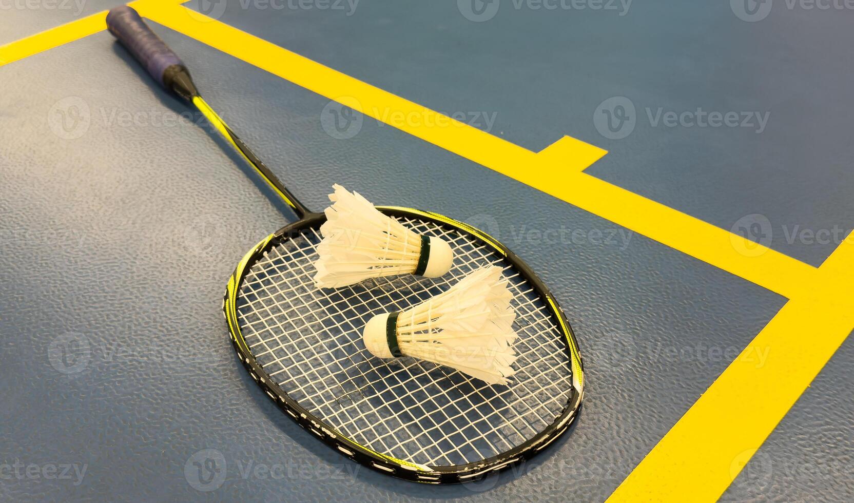 Shuttlecock on badminton racquet on floor. photo