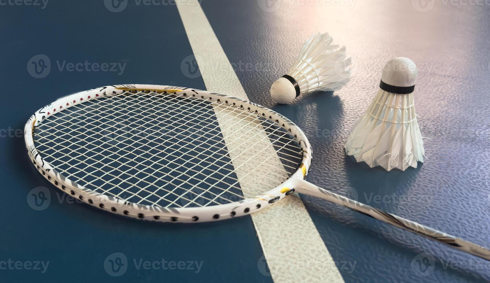 Broken badminton racket and used white badminton shuttlecocks on purple floor of the court, soft and selective focus, concept for badminton sport lovers around the world. photo