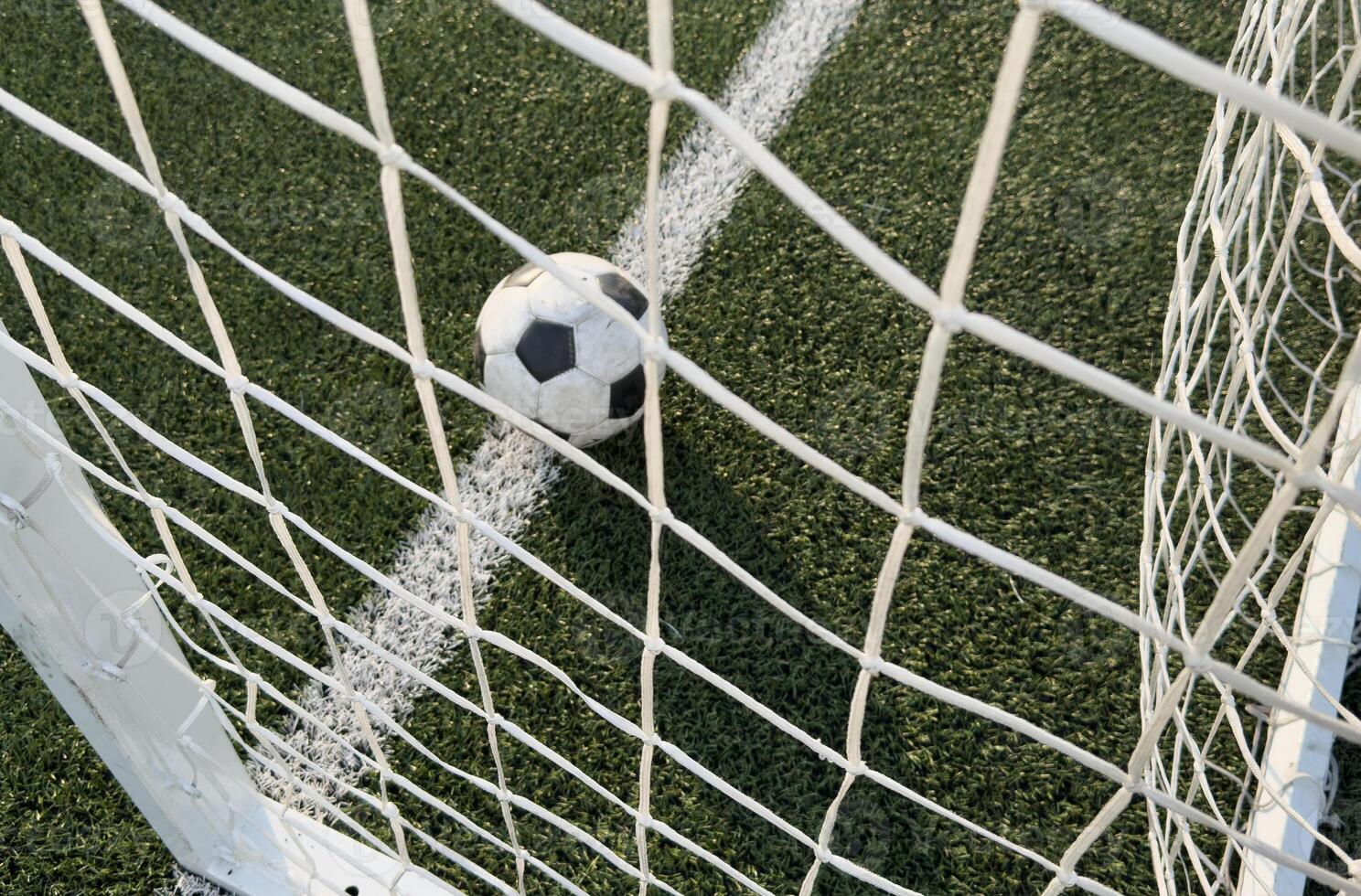 Soccer ball in goal on blue background photo