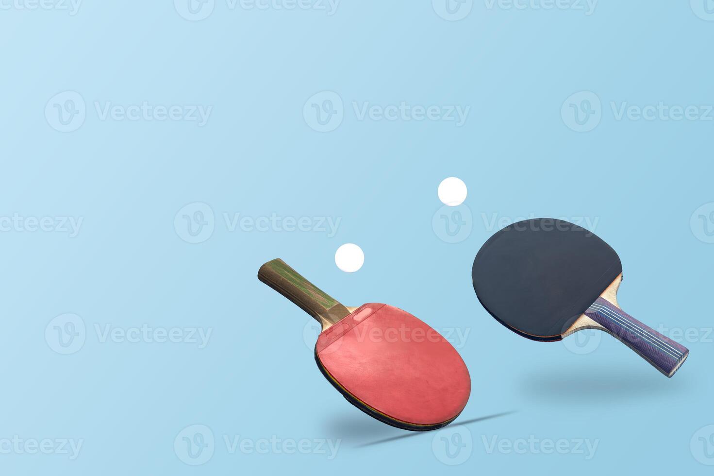 Red ping pong table tennis paddle rackets with ball on blue background. Summer sport activity concept. photo