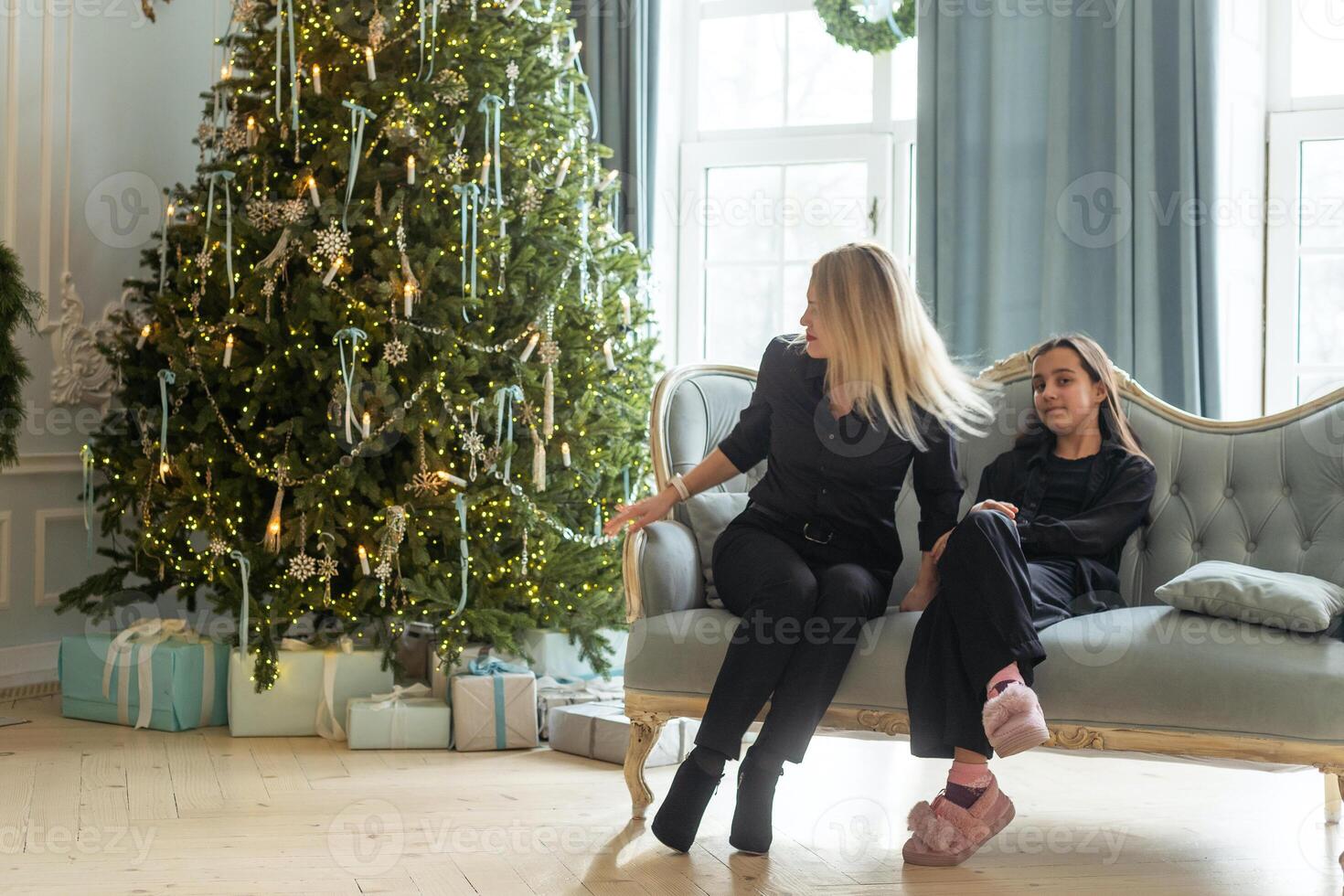 Happy Caucasian mother and her daughter are during Christmas, decorating a Christmas tree and having fun photo