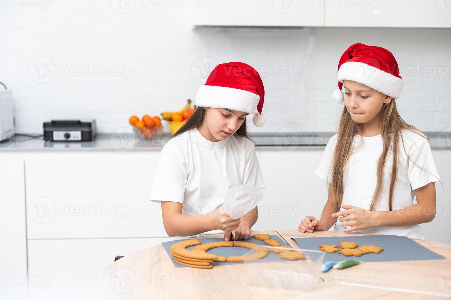 Two girls sisters are playing around in the kitchen after making Christmas cookies, they draw with flour on the table and on their faces. Christmas, New Year concept photo