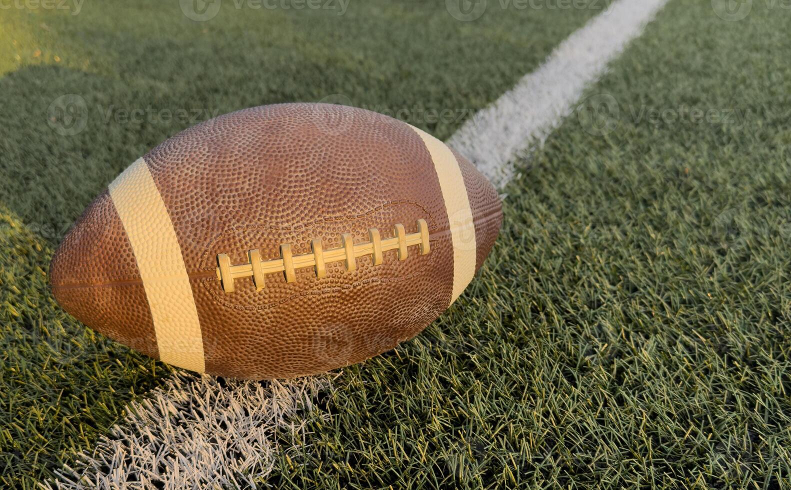 View from above of an American Football sitting on a grass football field on the yard line. Generic Sports image photo
