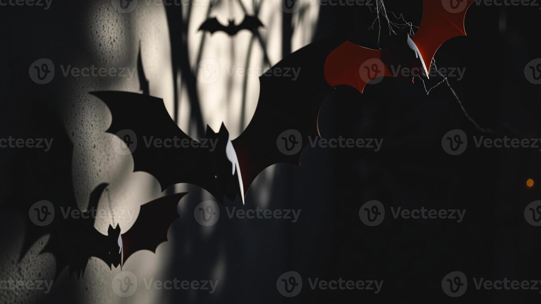 black paper bats hanging against a textured background photo