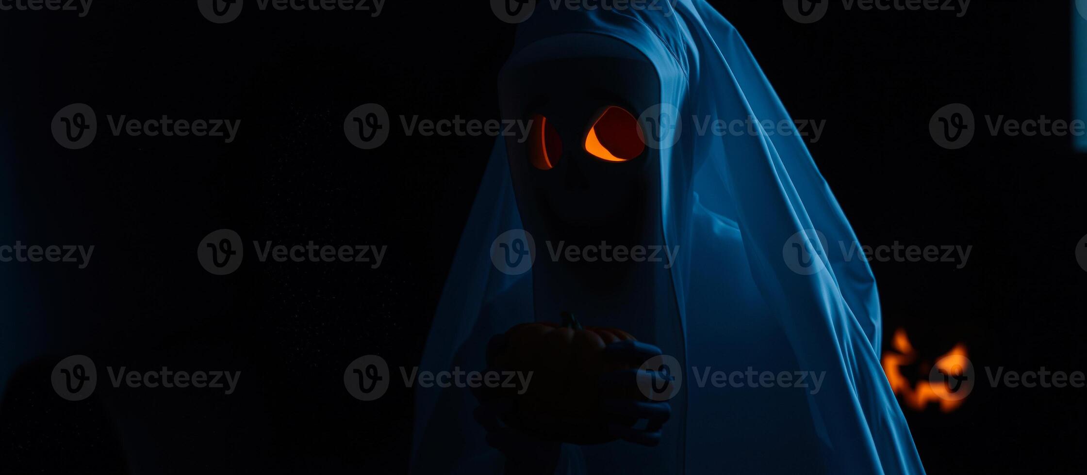 ghostly figure holds a small pumpkin the dark photo
