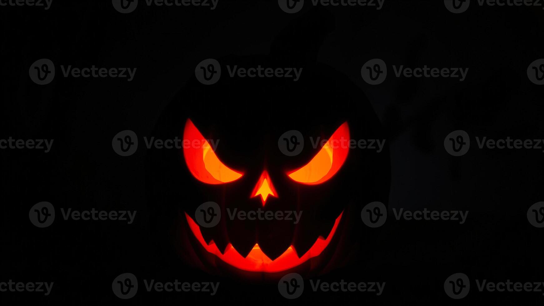 glowing jack-o'-lantern with an evil grin stares into the darkness photo