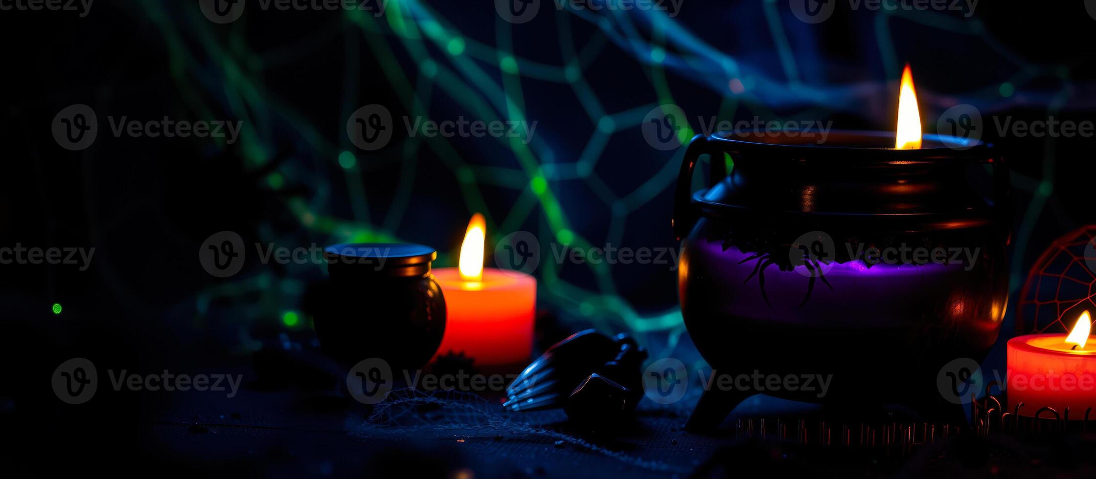 black cauldron with a spider on it illuminated by candlelight photo