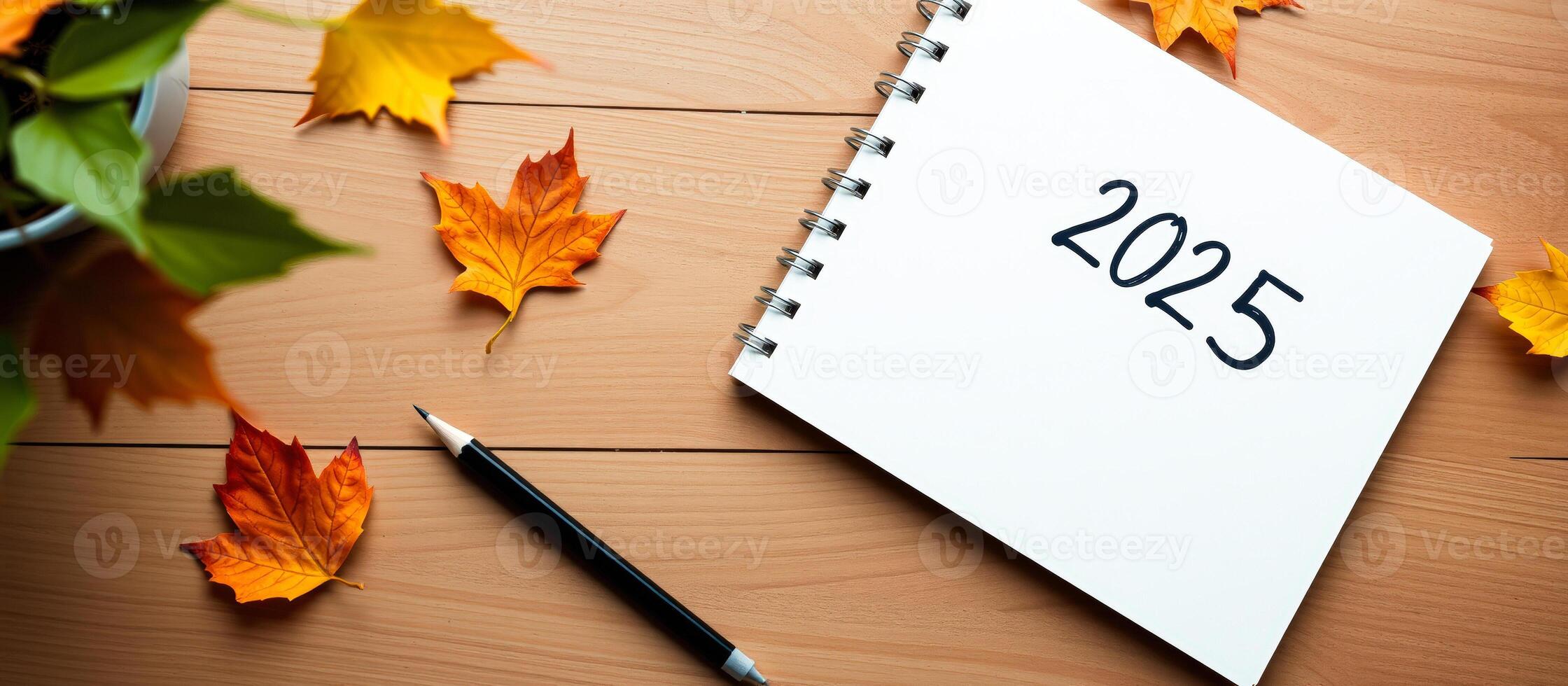 notebook with 2025 written on it surrounded by autumn leaves photo
