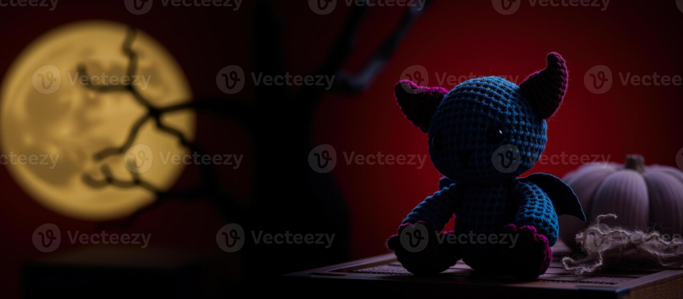 crocheted creature with pink horns wings sits against a red background photo