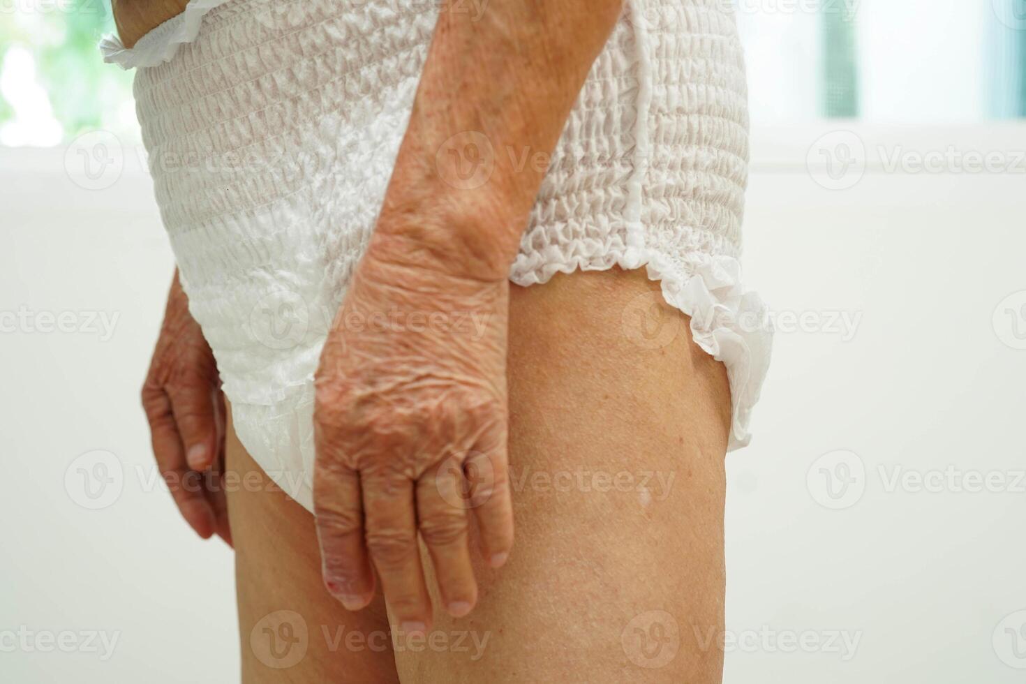 Asian senior woman patient wearing adult incontinence diaper pad in hospital. photo