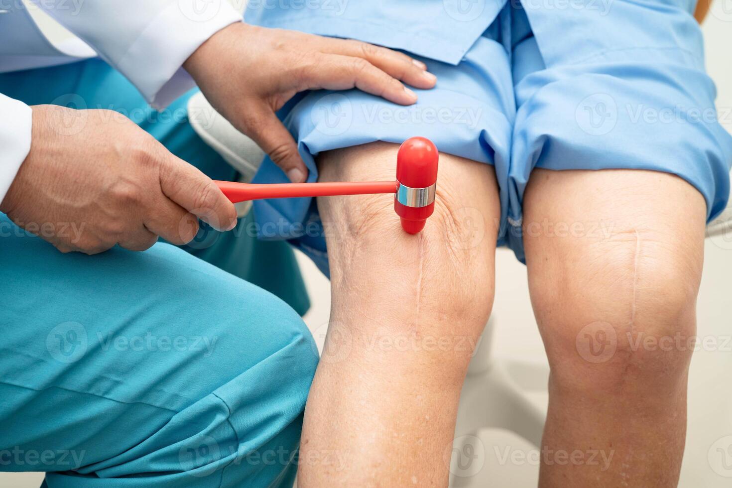 Asian doctor knock on knee reflex nerve for check and treatment senior patient in hospital. photo