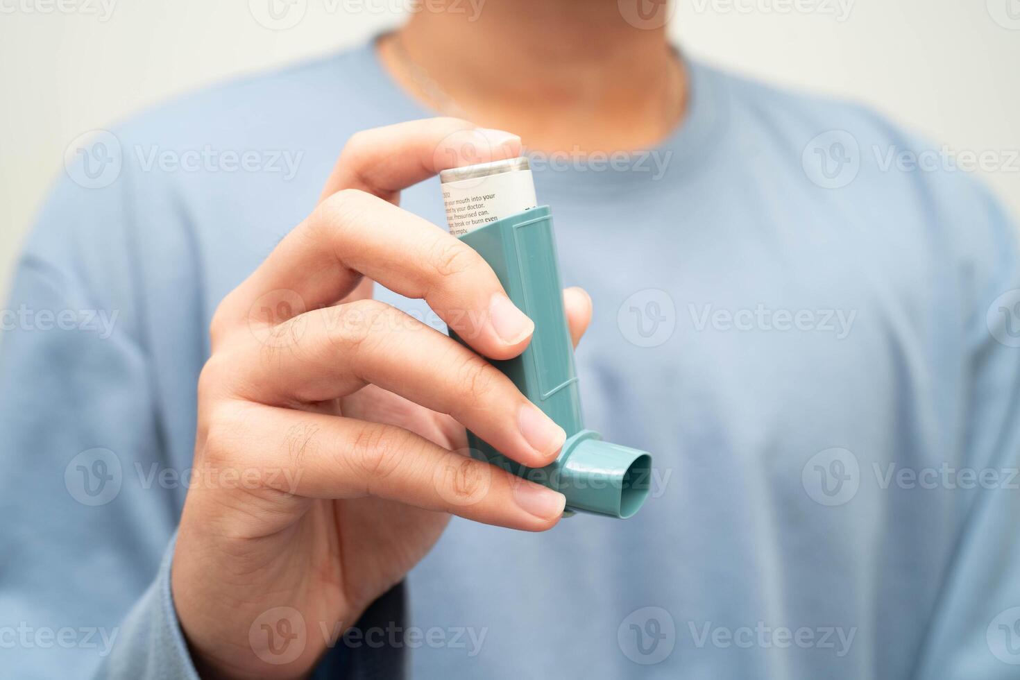 Asthma and chronic obstructive pulmonary disease COPD, Asian young man using metered dose inhaler MDI. photo