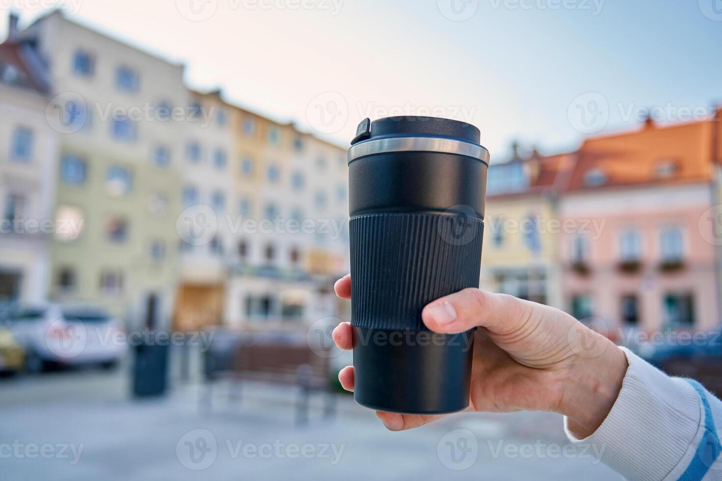 Woman holding reusable coffee cup outdoors in autumn photo