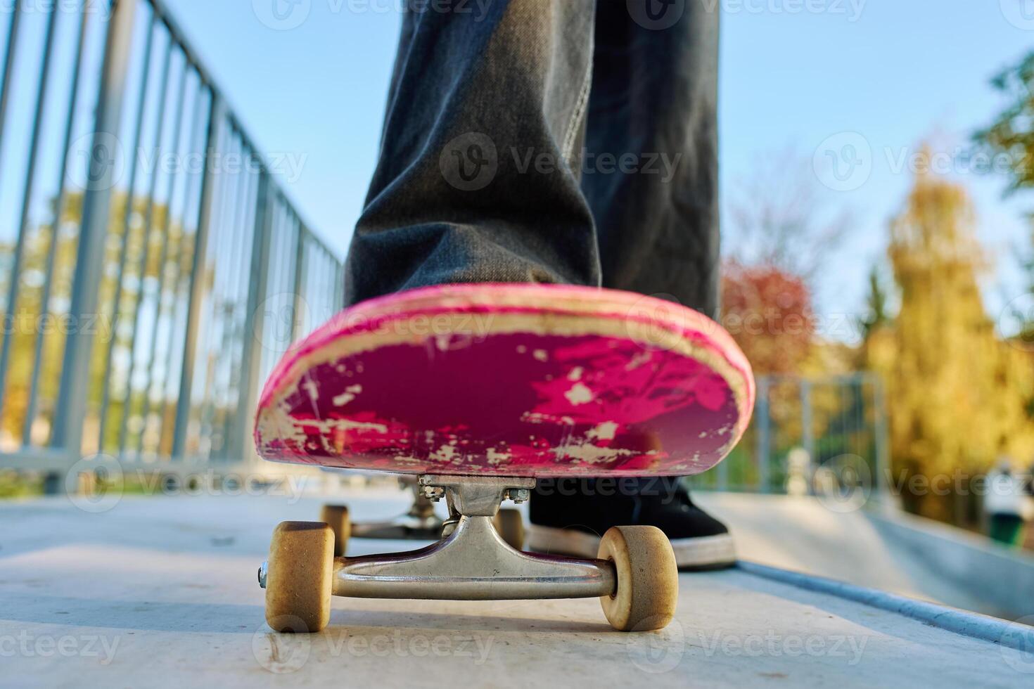 Skateboarder riding on pink skateboard at skatepark photo