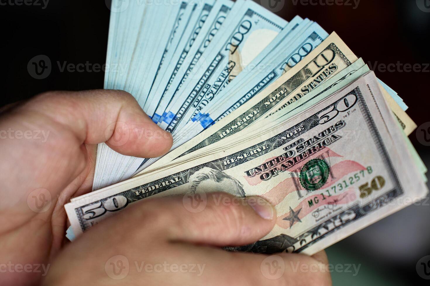 Man counting stack of dollar bills photo
