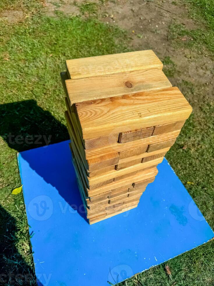 Outdoor wooden Jenga tower on a blue platform, ready for a fun garden game. High quality photo