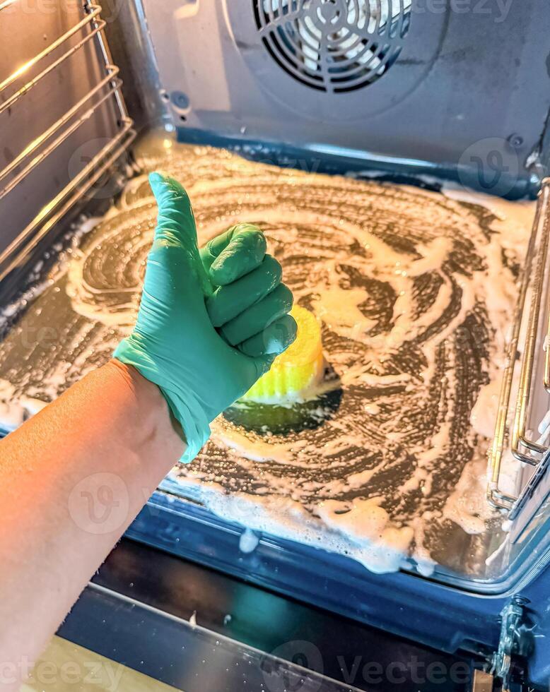 Thumbs Up for Clean, Oven Scrubbing with Soap and Gloves in Progress. High quality photo
