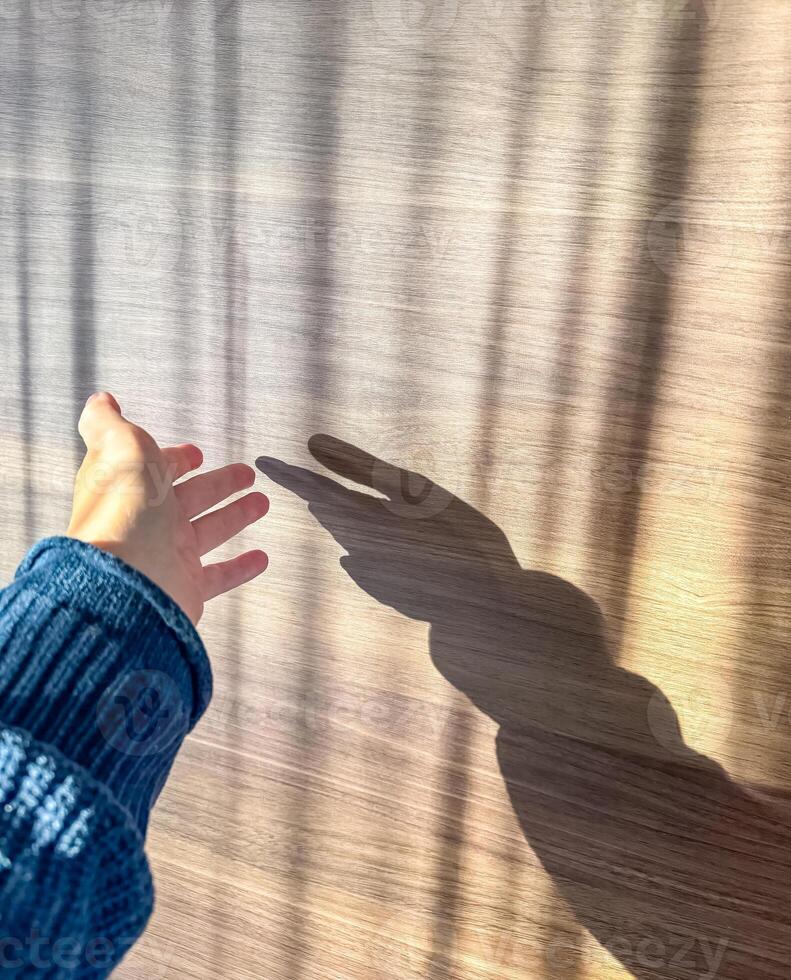 hand touching the wall exposed to sunlight on wooden background. High quality photo