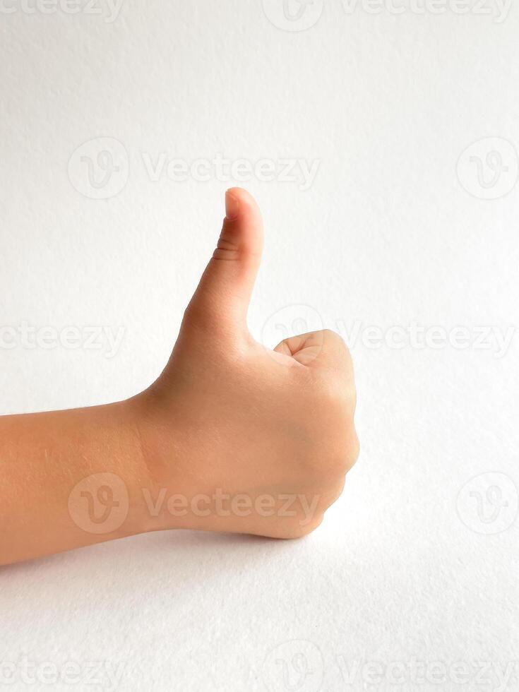 Childs hand giving a thumbs up with neutral background for positivity concept photo