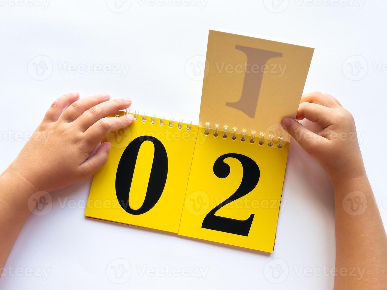 Childs hands flipping educational flashcards with numbers and letters on bright yellow background photo