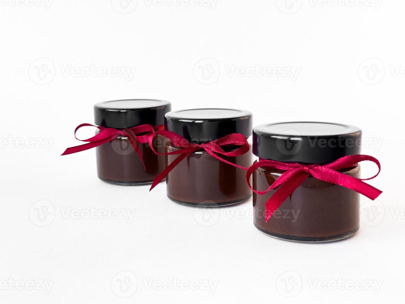 Gourmet chocolate jars with red ribbons on white background photo