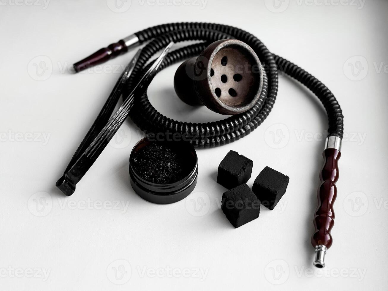 Traditional hookah set with hose, bowl, tongs, and charcoal on white background photo